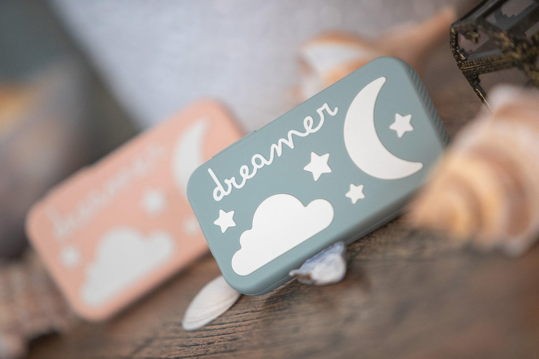 Baby sound machine with moon, stars, and cloud design on a wooden surface with seashells.