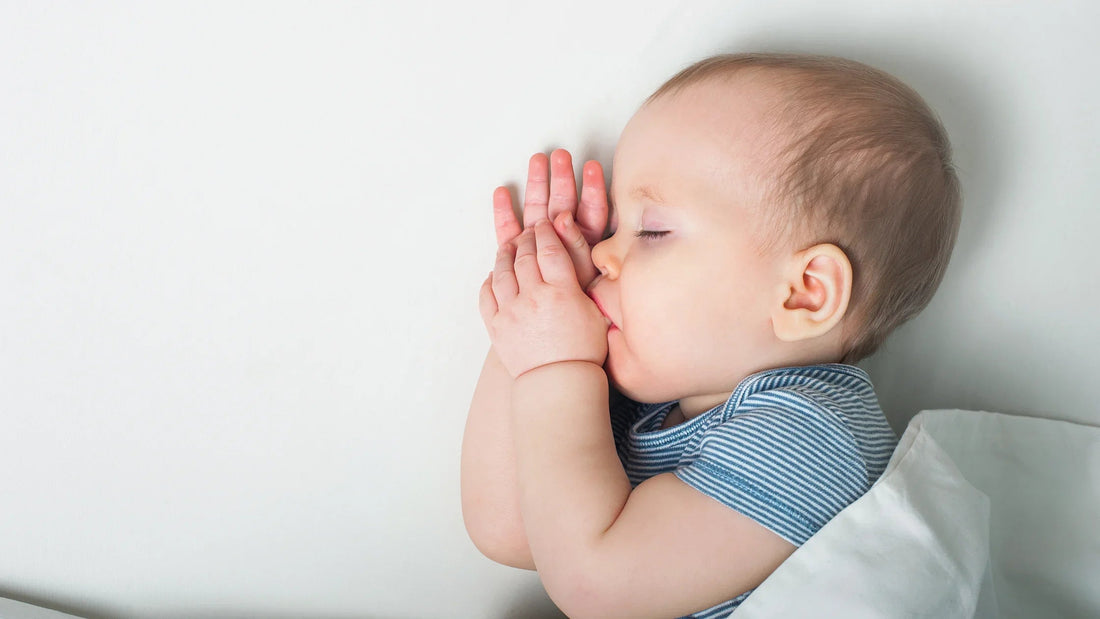 Sleeping baby sucking thumb under white blanket, peaceful infant sleep for bedtime routine