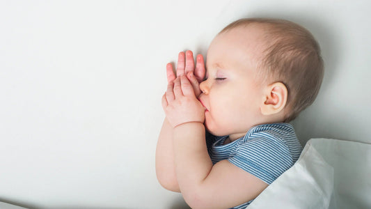 Sleeping baby sucking thumb under white blanket, peaceful infant sleep for bedtime routine