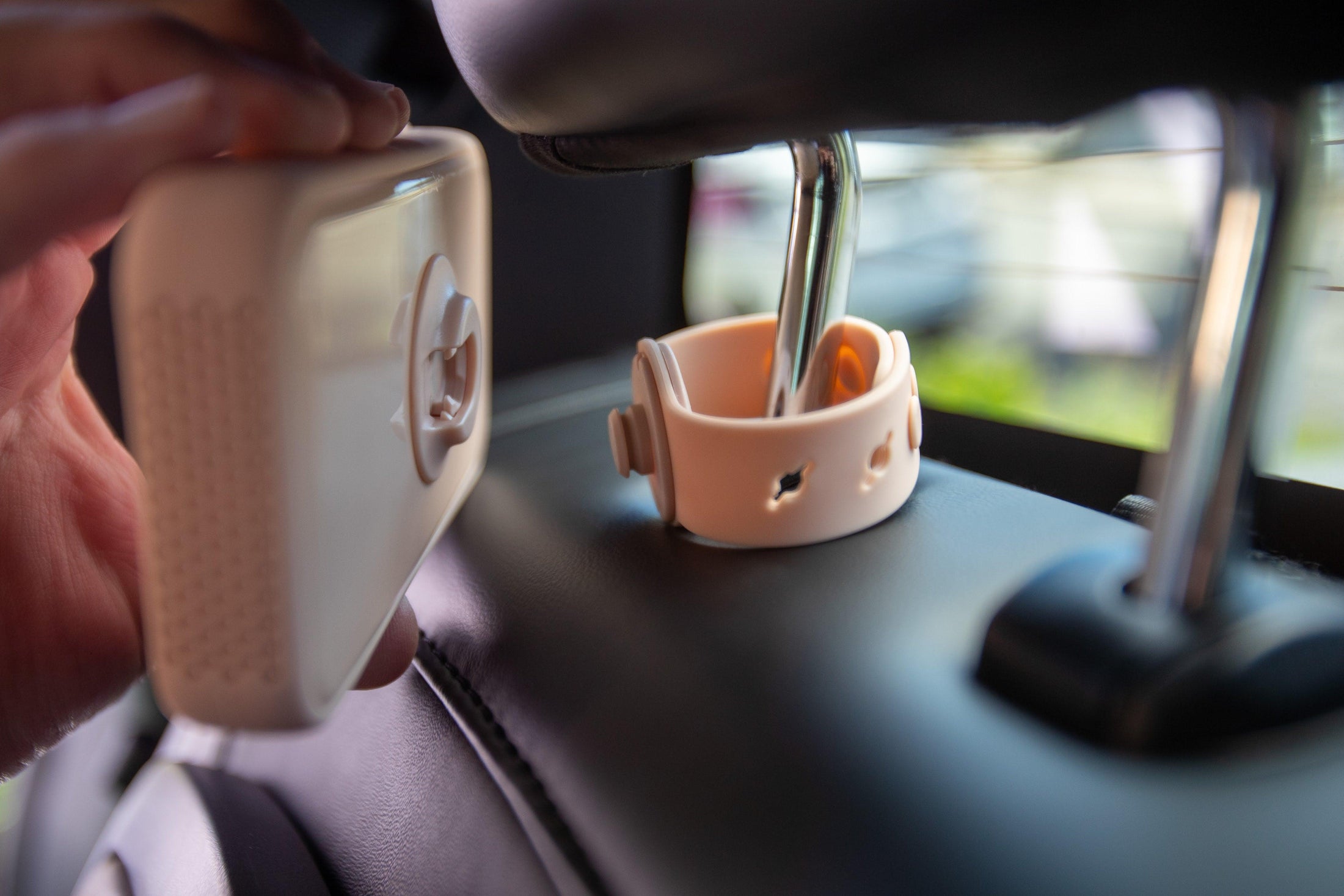 Dreamer baby sound machine being attached to magnetic mount on car headrest (Peach-Dreamer)