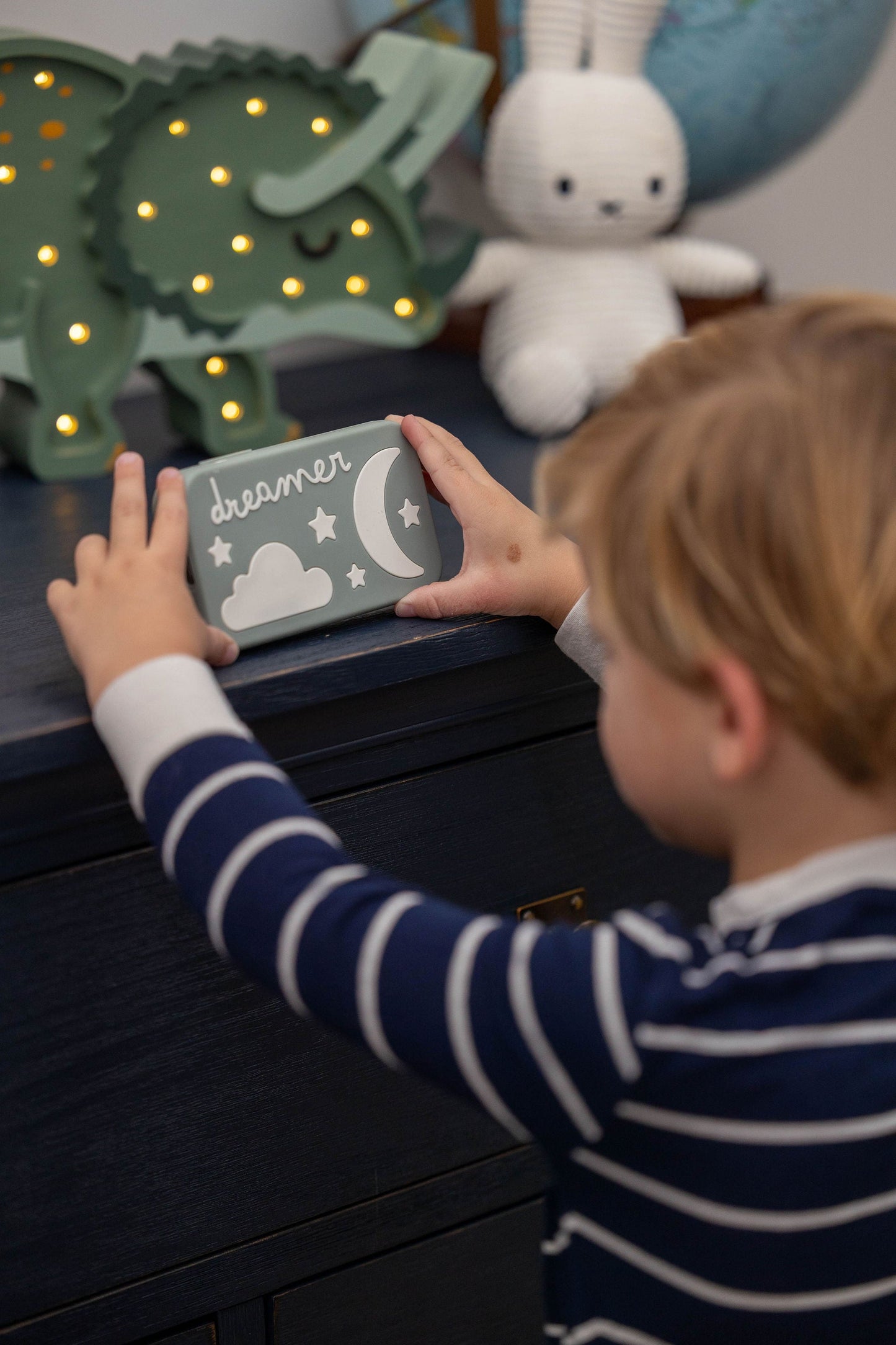 Toddler holding a Dreamer™ baby sound machine — the Duo bundle is designed for newborns through age 4