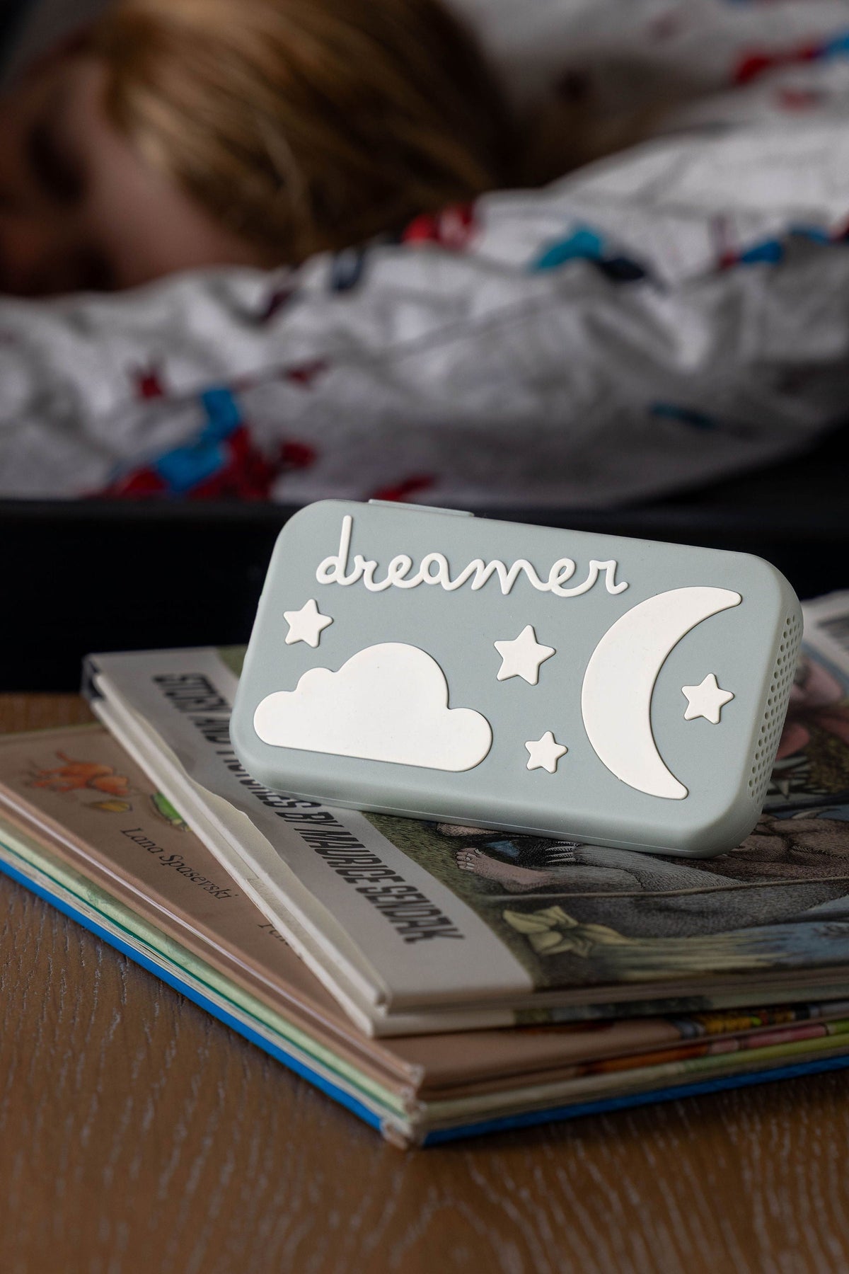 Sage green Dreamer™ baby sound machine from the Duo bundle on a stack of bedtime books