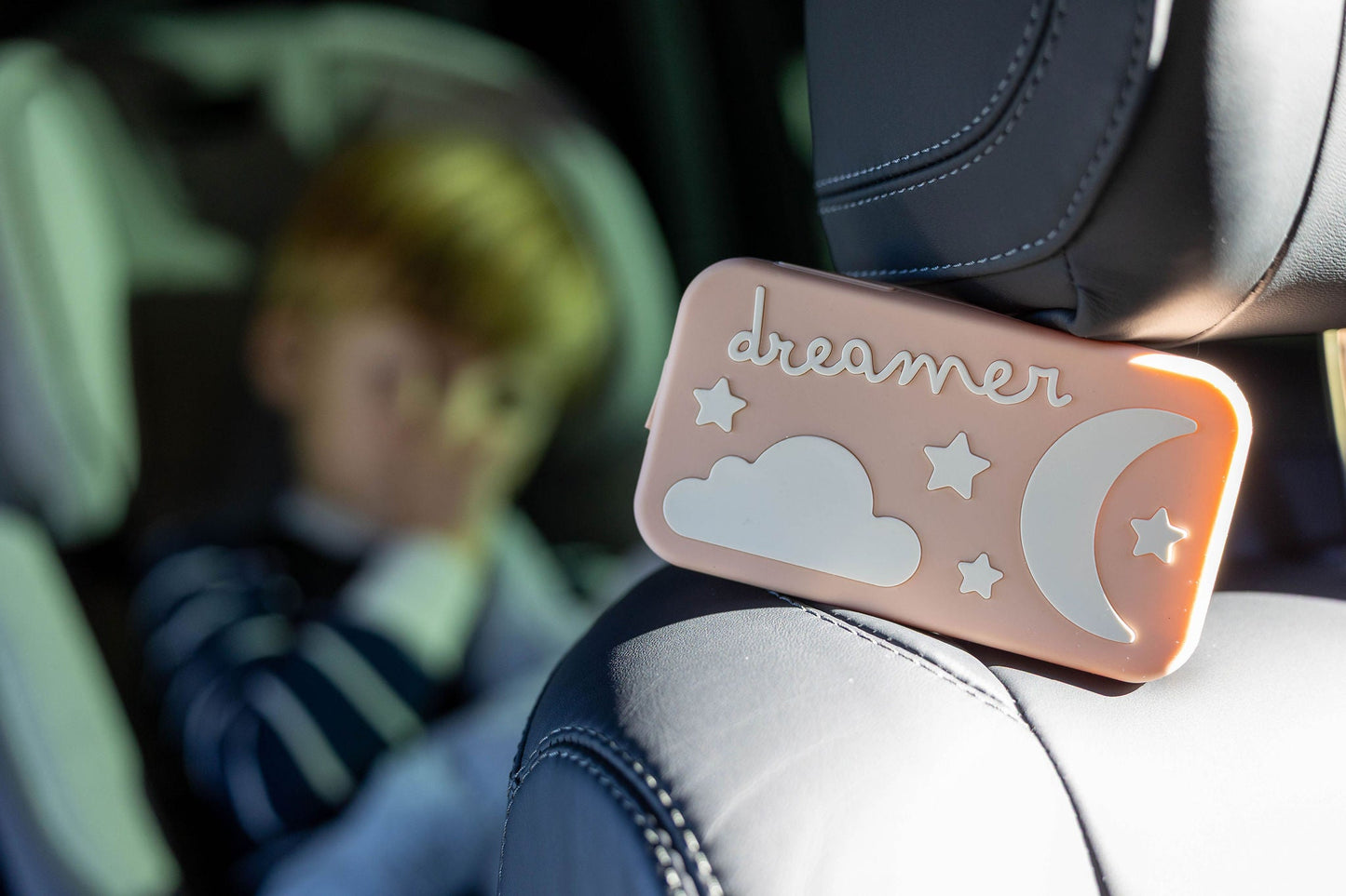 Peach Dreamer™ baby sound machine from the Duo bundle attached to a car seat headrest for travel